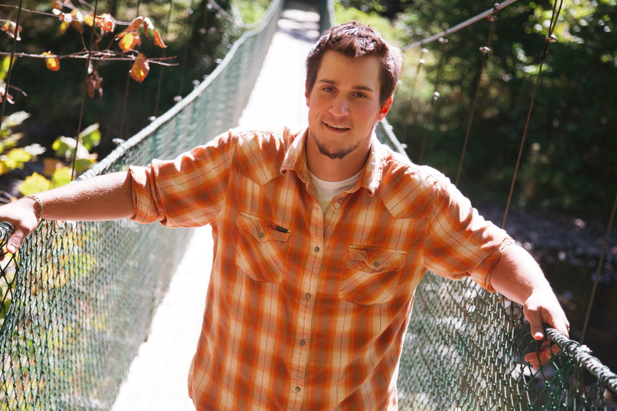 Male student hiking across suspension bridge